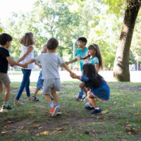 happy-children-playing-together-outdoors-dancing-around-on-grass-enjoying-outdoor-activities-and-having-fun-in-park-kids-party-or-friendship-concept